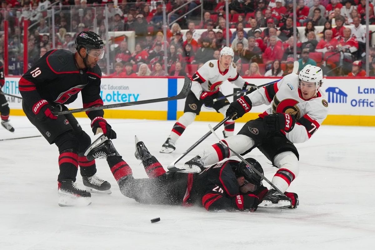 Apr 20, 2026; Raleigh, North Carolina, USA; Ottawa Senators center Ridly Greig (71) is tripped by Carolina Hurricanes defenseman Sean Walker (26) during the second period in game two of the first round of the 2026 Stanley Cup Playoffs at Lenovo Center. Mandatory Credit: James Guillory-Imagn Images
