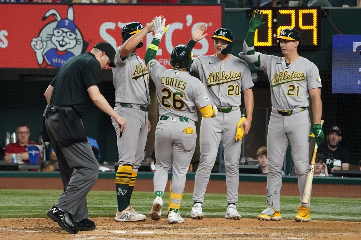 Apr 24, 2026; Arlington, Texas, USA;  Athletics left fielder Carlos Cortes (26) is greeted at home plate by first baseman Nick Kurtz (16), second baseman Zack Gelof (20) and left fielder Tyler Soderstrom (21) after hitting a three-run home run against the Texas Rangers during the fifth inning at Globe Life Field. Mandatory Credit: Raymond Carlin III-Imagn Images