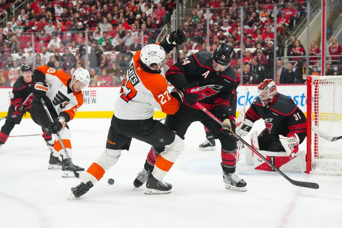 May 4, 2026; Raleigh, North Carolina, USA; Carolina Hurricanes defenseman Jaccob Slavin (74) and Philadelphia Flyers left wing Noah Cates (27) battle over the puck in the first overtime in game two of the second round of the 2026 Stanley Cup Playoffs at Lenovo Center. Mandatory Credit: James Guillory-Imagn Images