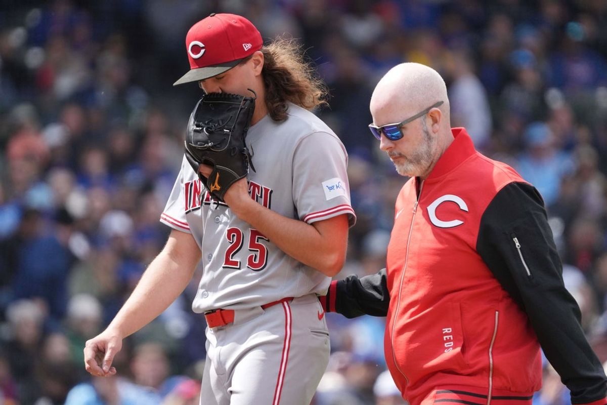 May 7, 2026; Chicago, Illinois, USA; Cincinnati Reds pitcher Rhett Lowder (25) leaves the game against the Chicago Cubs with the team trainer during the fourth inning at Wrigley Field. Mandatory Credit: David Banks-Imagn Images