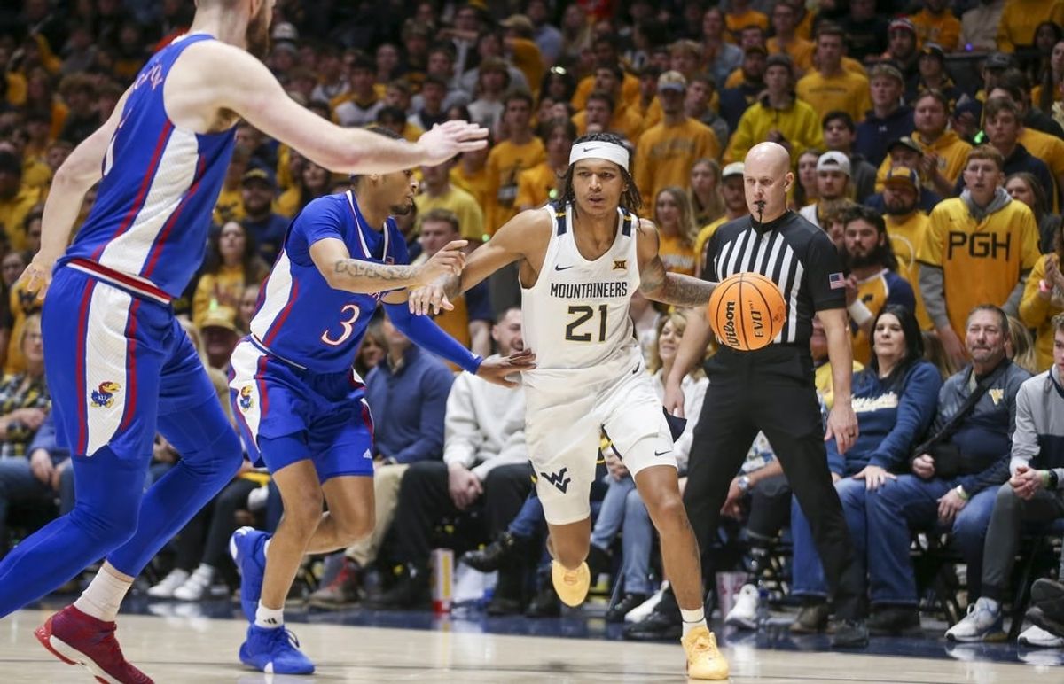 Jan 20, 2024; Morgantown, West Virginia, USA; West Virginia Mountaineers guard RaeQuan Battle (21) dribbles the ball past Kansas Jayhawks guard Dajuan Harris Jr. (3) during the second half at WVU Coliseum.
