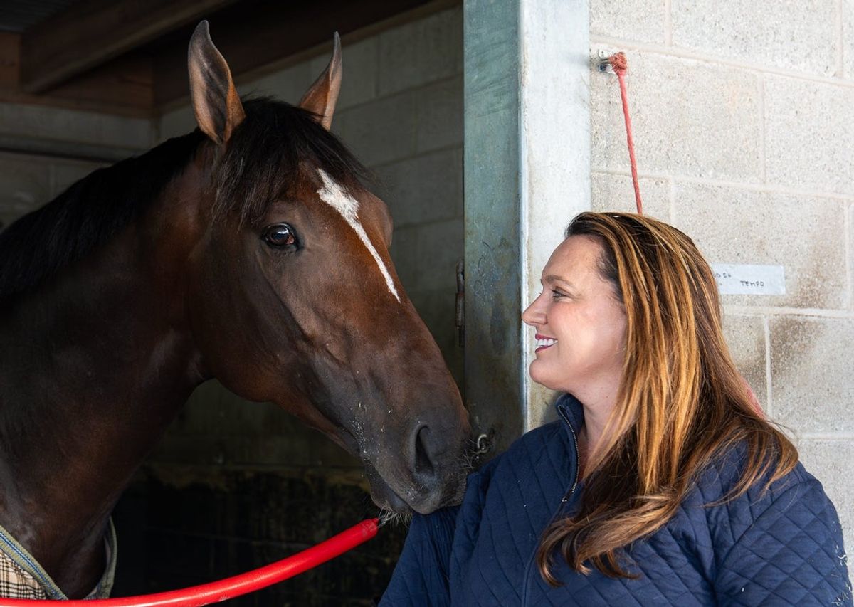 Cherie DeVaux smiles as Golden Tempo tugs on the sleeve of her coat inside her barn at Keeneland Race Course in Lexington, Ky., on May 14, 2026.