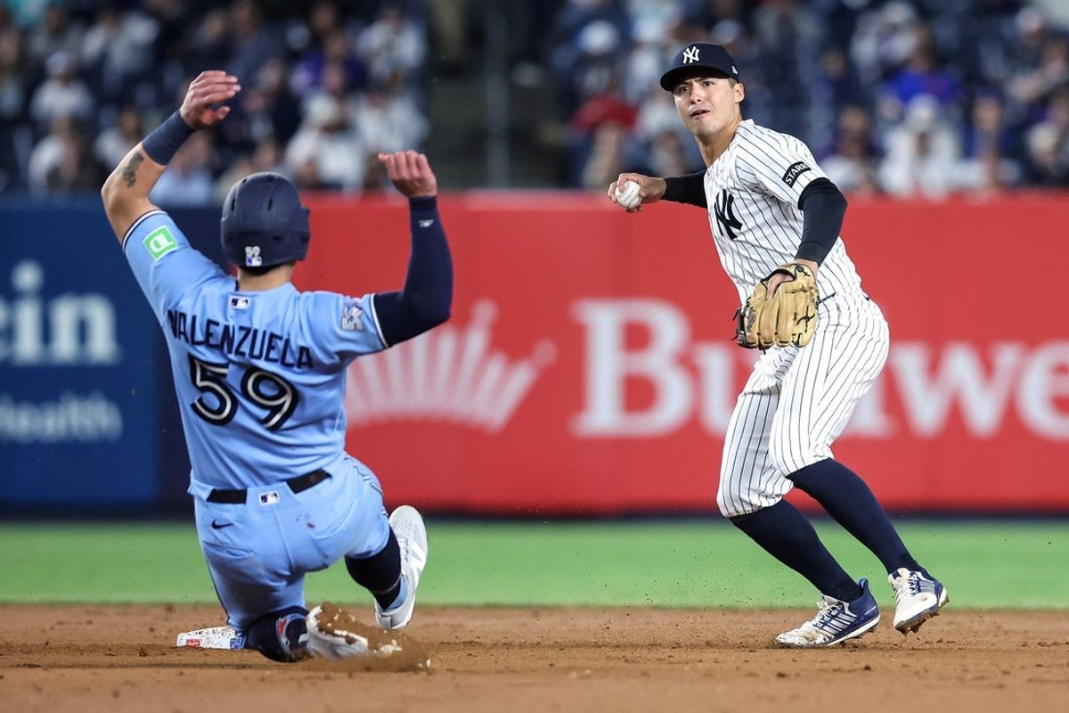 New York Yankees shortstop Anthony Volpe throws past Toronto Blue Jays catcher Brandon Valenzuela to complete a double play in the ninth inning  at Yankee Stadium.