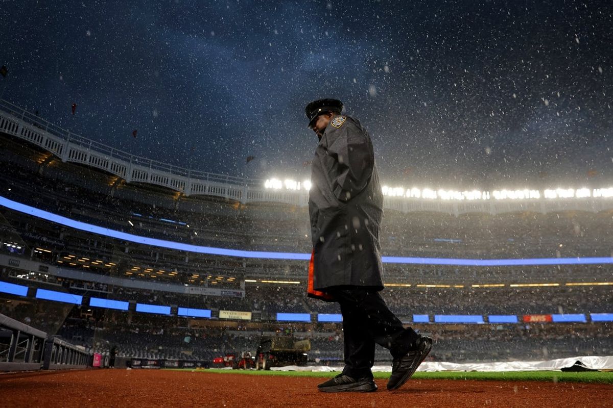 Jun 6, 2026; Bronx, New York, USA; An NYPD officer walks off the field as the rain picks up during a rain delay before the start of a game between the New York Yankees and Boston Red Sox at Yankee Stadium. Mandatory Credit: Brad Penner-Imagn Images