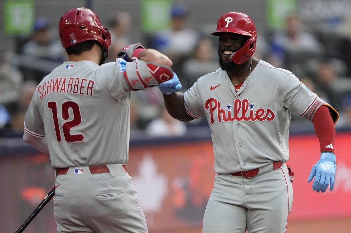 8 de junho de 2026; Toronto, Ontário, CAN; O rebatedor designado do Philadelphia Phillies, Kyle Schwarber (12), parabeniza o defensor direito Adolis Garcia (53) por seu home run de duas corridas contra o Toronto Blue Jays durante o segundo turno no Rogers Centre. Crédito obrigatório: John E. Sokolowski-Imagn Images