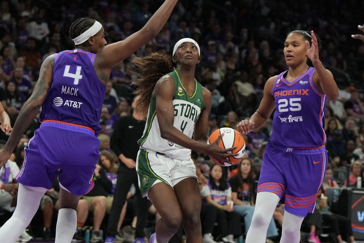Jun 20, 2026; Phoenix, Arizona, USA; Seattle Storm guard Flau'jae Johnson (4) drives between Phoenix Mercury forward Natasha Mack (4) and forward Alyssa Thomas (25)in the second half at Mortgage Matchup Center. Mandatory Credit: Rick Scuteri-Imagn Images