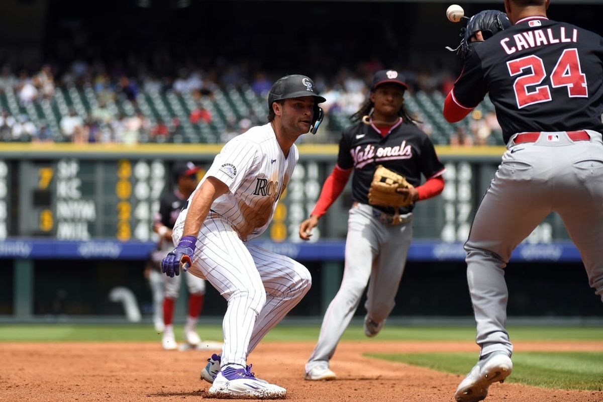 Jul 22, 2026; Denver, Colorado, USA; Colorado Rockies infielder Kyle Karros (12) is caught in a run down against Washington Nationals pitcher Cade Cavalli (24) in the second inning at Coors Field. Mandatory Credit: Christopher Hanewinckel-Imagn Images