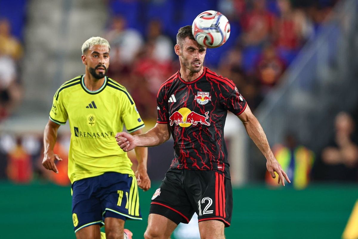 Aug 19, 2026; Harrison, New Jersey, USA; New York Red Bulls defender Dylan Nealis (12) heads the ball in front of Nashville SC forward Elias Saad (11) during the first half at Sports Illustrated Stadium. Mandatory Credit: Vincent Carchietta-Imagn Images