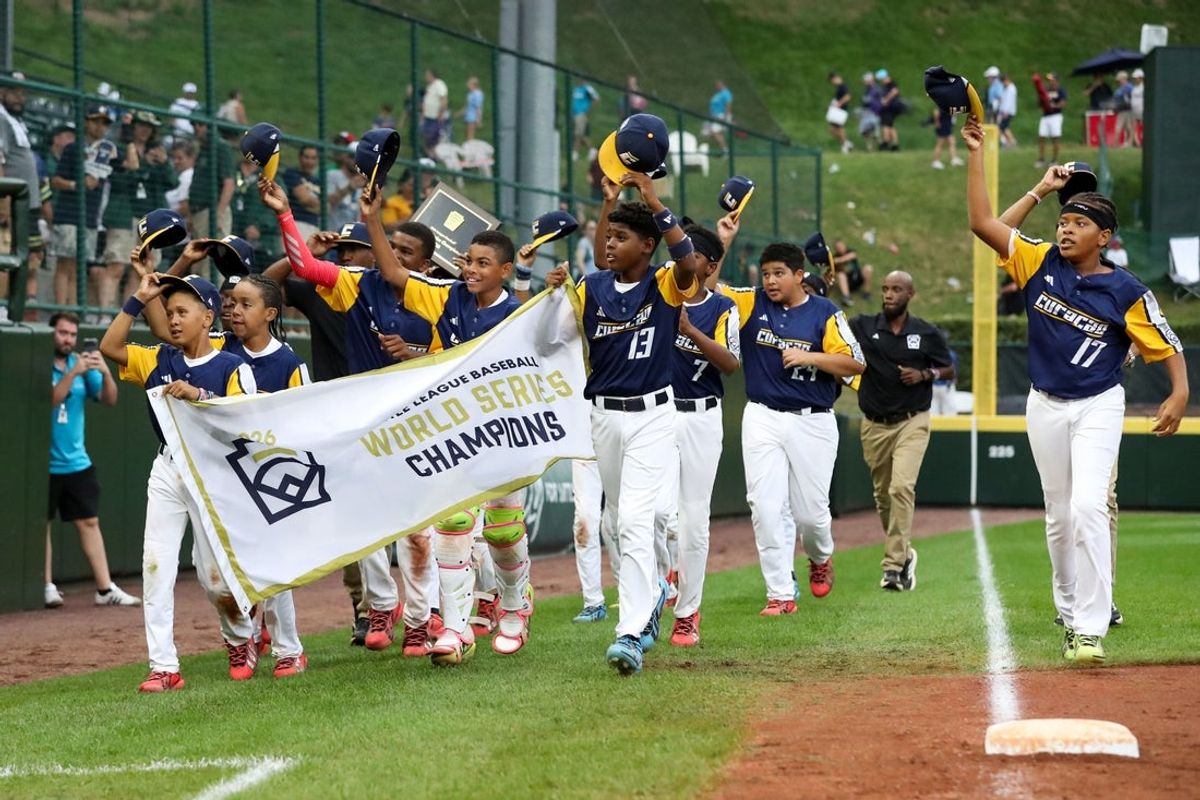 Aug 30, 2026; South Williamsport, PA, USA;  Curacao Region players and coaches tip their caps to the fans while running with the championship banner after defeating the Mountain Region 11-2 to win the Little League World Series championship game at Howard J. Lamade Stadium.  Mandatory Credit: Matthew O'Haren-Imagn Images