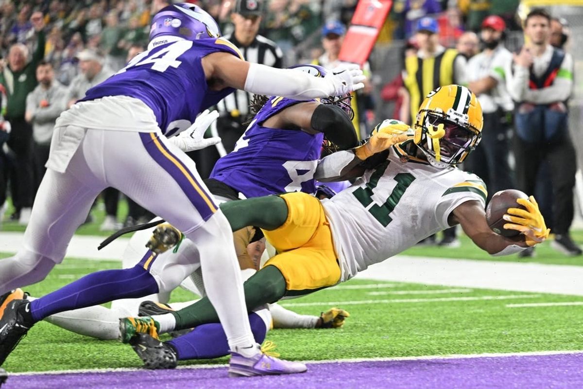 Dec 31, 2023; Minneapolis, Minnesota, USA; Green Bay Packers wide receiver Jayden Reed (11) scores a touchdown  as Minnesota Vikings safety Josh Metellus and safety Camryn Bynum (24) attempt to make the tackle during the second quarter at U.S. Bank Stadium.
