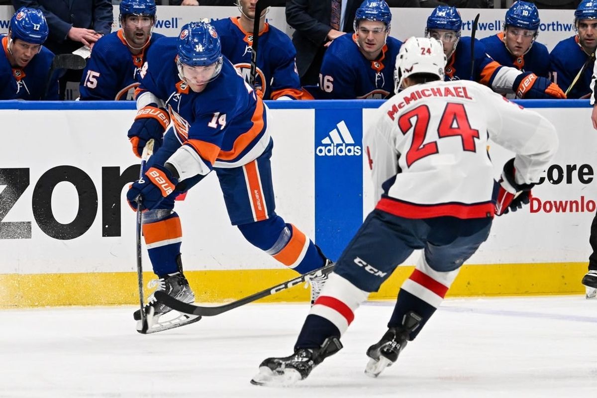 Dec 29, 2023; Elmont, New York, USA; New York Islanders center Bo Horvat (14) keeps the puck in the zone defended by Washington Capitals center Connor McMichael (24) during the second period at UBS Arena.