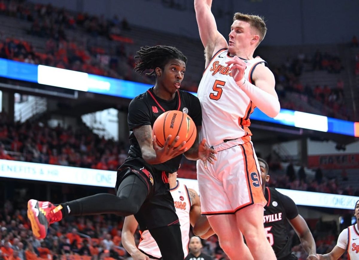 Feb 7, 2024; Syracuse, New York, USA; Louisville Cardinals guard Ty-Laur Johnson (4) passes the ball under the basket with Syracuse Orange guard Justin Taylor (5) defending in the first half at the JMA Wireless Dome.