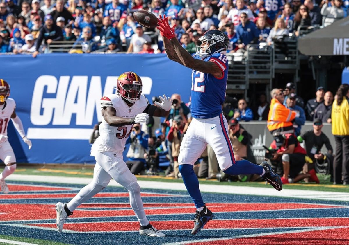 Oct 22, 2023; East Rutherford, New Jersey, USA; New York Giants tight end Darren Waller (12) catches a touchdown pass during the first half in front of Washington Commanders linebacker Cody Barton (57) at MetLife Stadium.