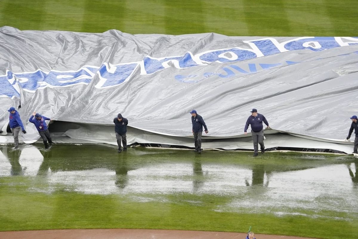 Apr 7, 2024; Chicago, Illinois, USA; The grounds crew takes the tarp off the field after a two hour rain delay in a game between the Chicago Cubs and the Los Angeles Dodgers at Wrigley Field.