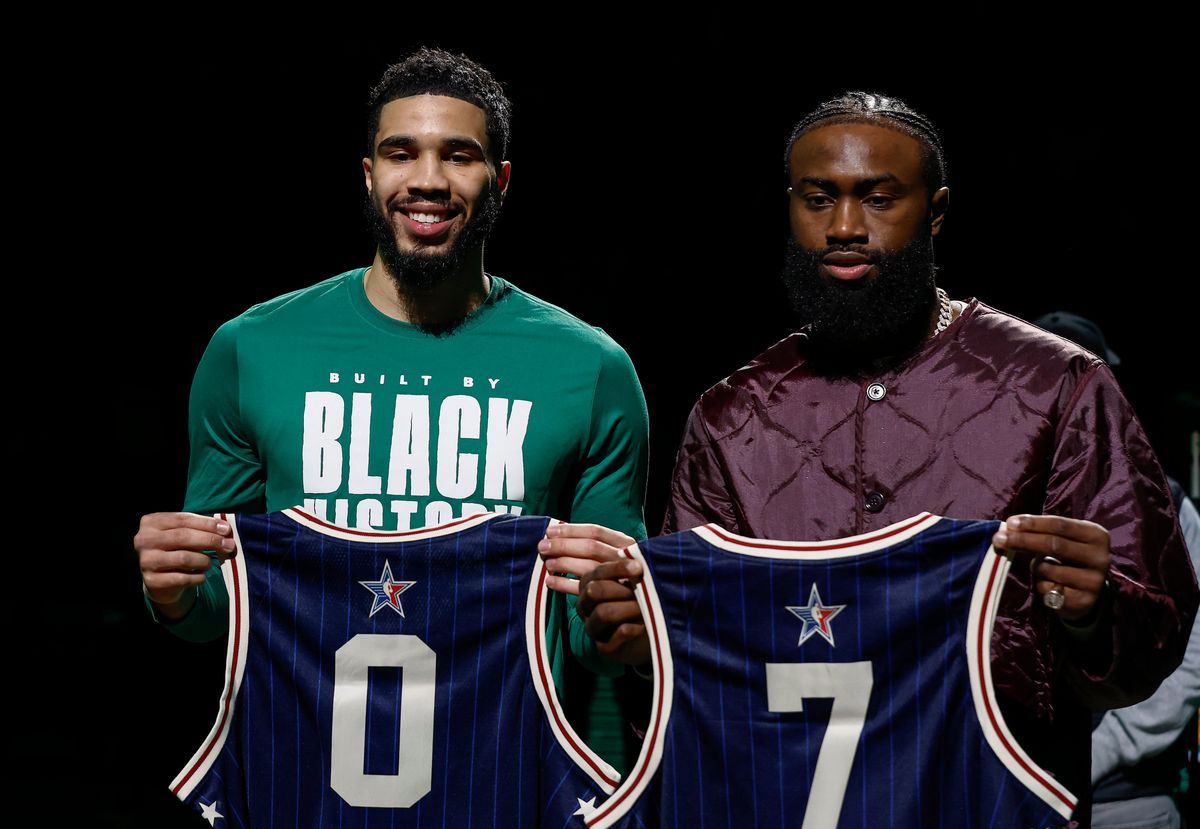 Jayson Tatum (l.) and Jaylen Brown hold up their All-Star jerseys