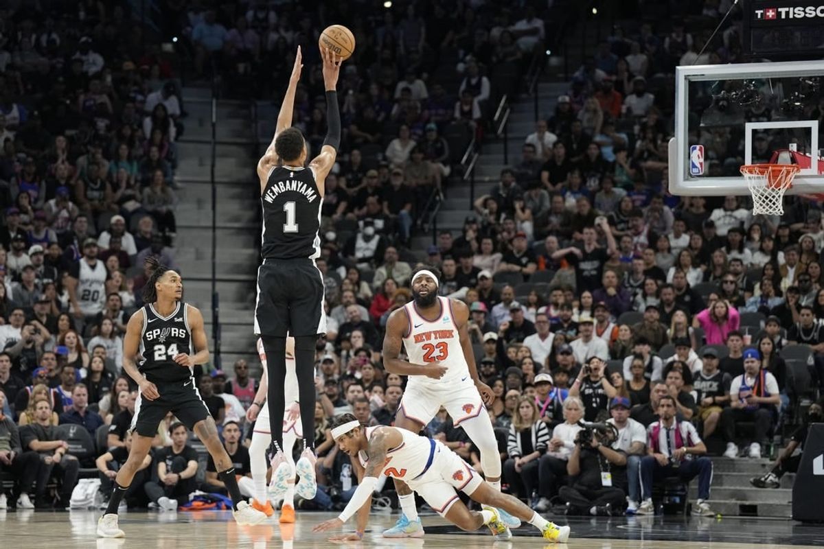 Mar 29, 2024; San Antonio, Texas, USA; San Antonio Spurs forward Victor Wembanyama (1) shoots a three pointer over New York Knicks guard Miles McBride (2) during overtime at Frost Bank Center.