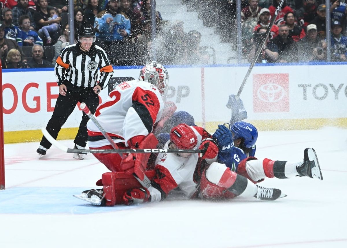 Oct 20, 2026; Vancouver, British Columbia, CAN;  Vancouver Canucks left wing Arshdeep Bains (13) crashes into Carolina Hurricanes goaltender Pyotr Kochetkov (52) and left wing Bradly Nadeau (29) during the second period at Rogers Arena.  Mandatory Credit: Simon Fearn-Imagn Images