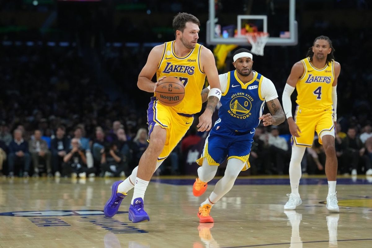 Oct 21, 2026; Los Angeles, California, USA; Los Angeles Lakers guard Luka Doncic (77) dribbles the ball against Golden State Warriors guard Gary Payton II (0) in the first half at Crypto.com Arena. Mandatory Credit: Kirby Lee-Imagn Images