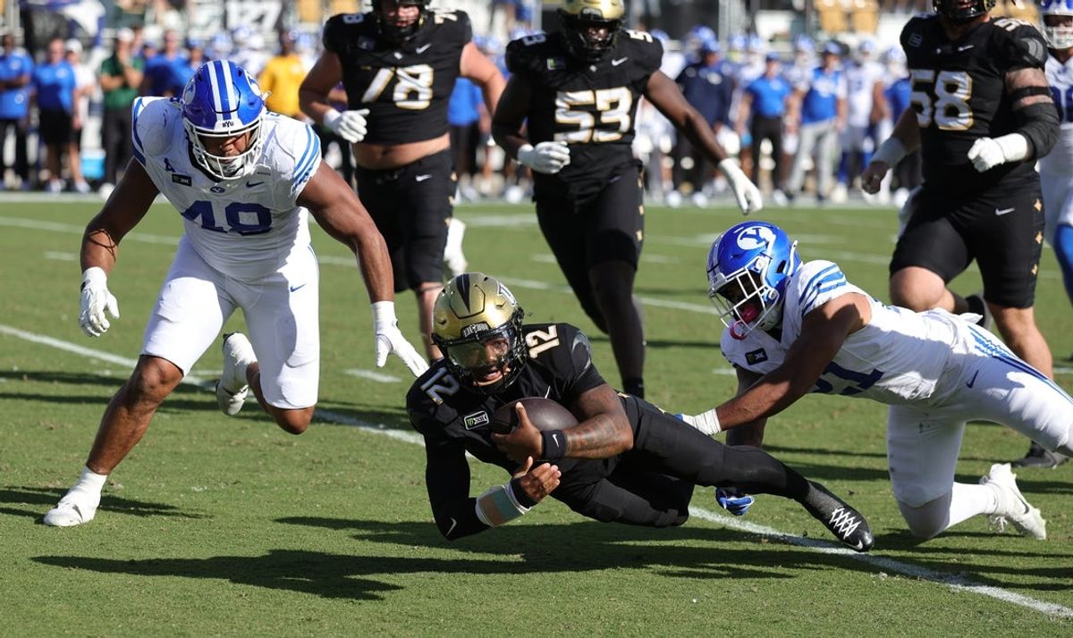 Oct 24, 2026; Orlando, Florida, USA;  Central Florida Knights quarterback Keyone Jenkins (12) is tackled by Brigham Young Cougars linebacker Miles Hall (21) during the first half at Acrisure Bounce House.  Mandatory Credit: Mike Watters-Imagn Images