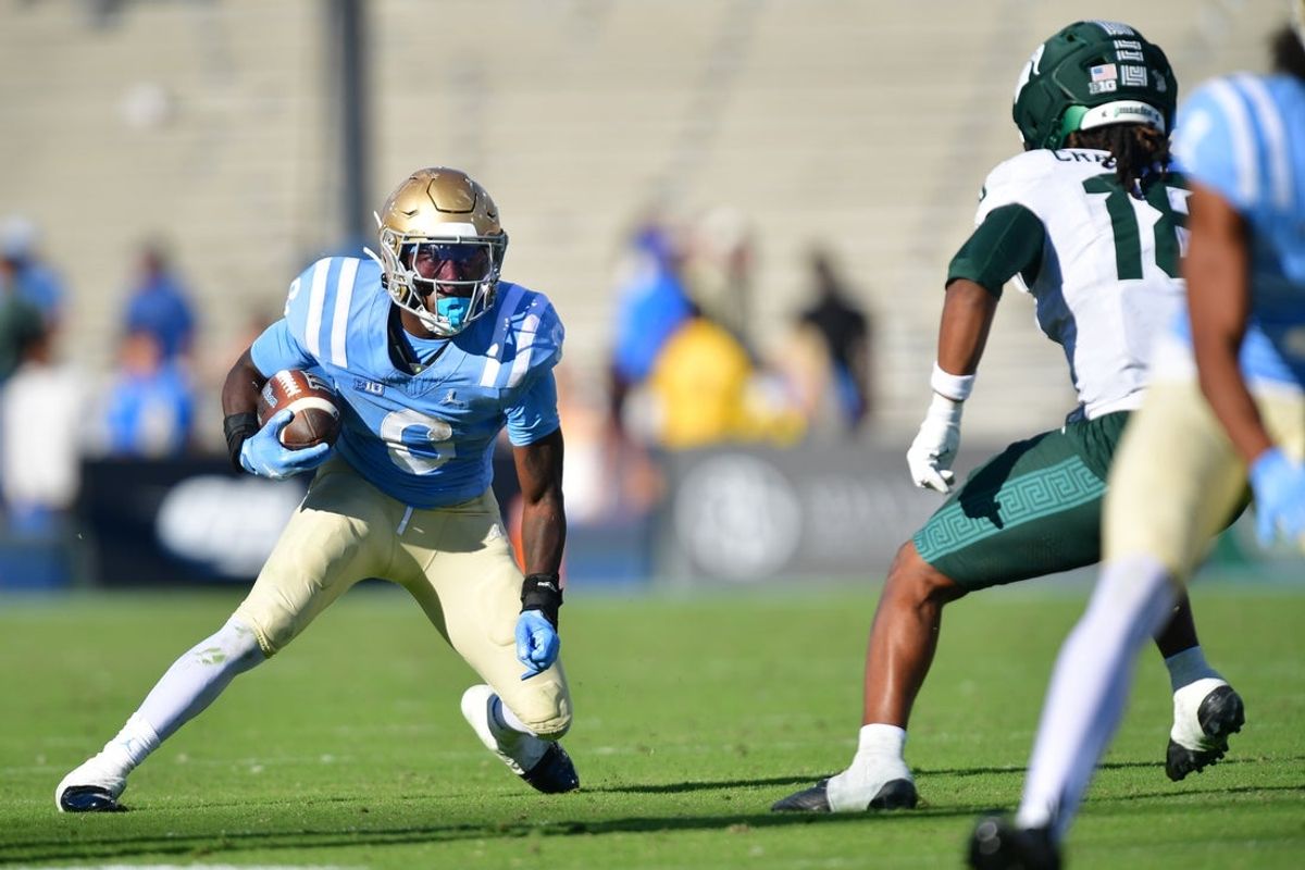 Oct 24, 2026; Pasadena, California, USA;  UCLA Bruins running back Anthony Woods (6) runs the ball as Michigan State Spartans linebacker Dion Crawford (18) defends during the second half at Rose Bowl.  Mandatory Credit: Gary A. Vasquez-Imagn Images