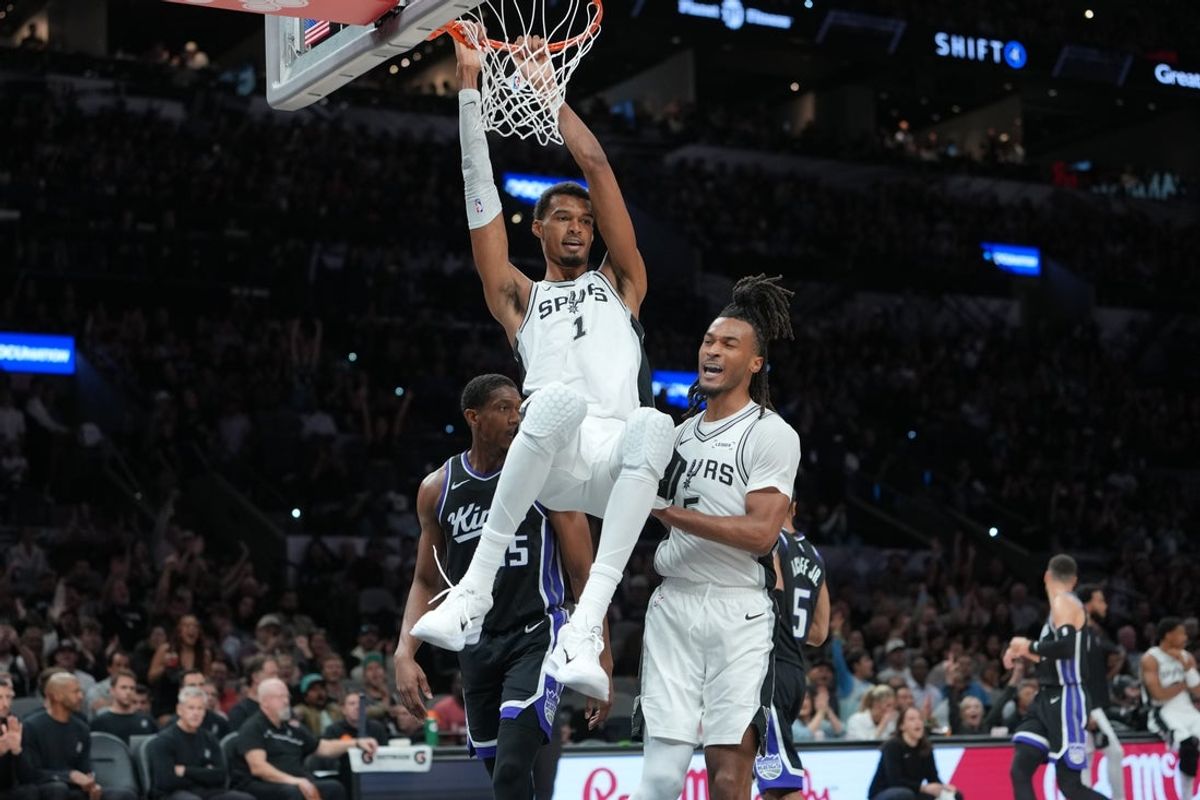 Oct 27, 2026; San Antonio, Texas, USA;  San Antonio Spurs forward Victor Wembanyama (1) hangs on the rim in front of Sacramento Kings forward De'andre Hunter (15) and San Antonio Spurs guard Stephon Castle (5) in the second half at Frost Bank Center.  Mandatory Credit: Daniel Dunn-Imagn Images