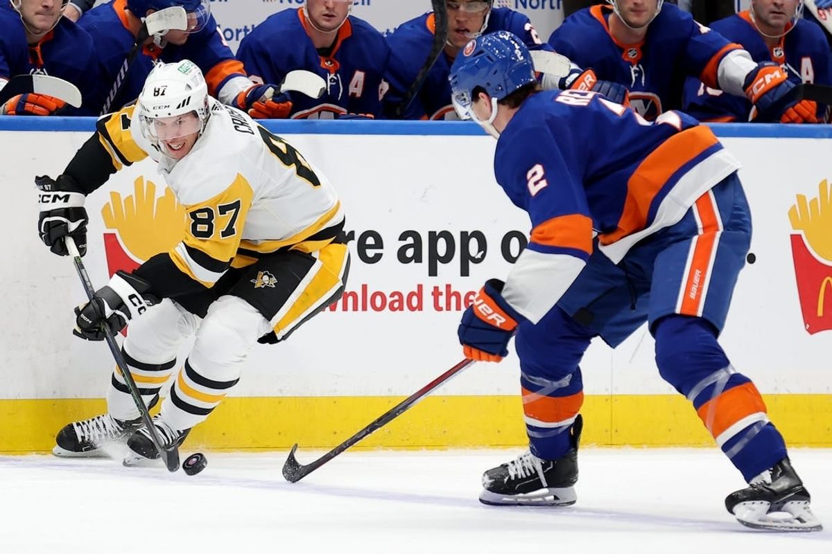 Dec 27, 2023; Elmont, New York, USA; Pittsburgh Penguins center Sidney Crosby (87) controls the puck against New York Islanders defenseman Mike Reilly (2) during the third period at UBS Arena.