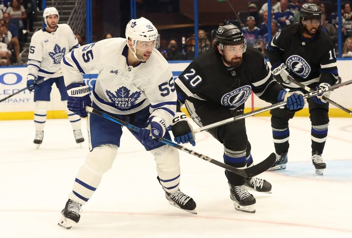 Apr 17, 2024; Tampa, Florida, USA; Toronto Maple Leafs defenseman Mark Giordano (55) and Tampa Bay Lightning left wing Nicholas Paul (20) skate for a loose puck during the third period at Amalie Arena.