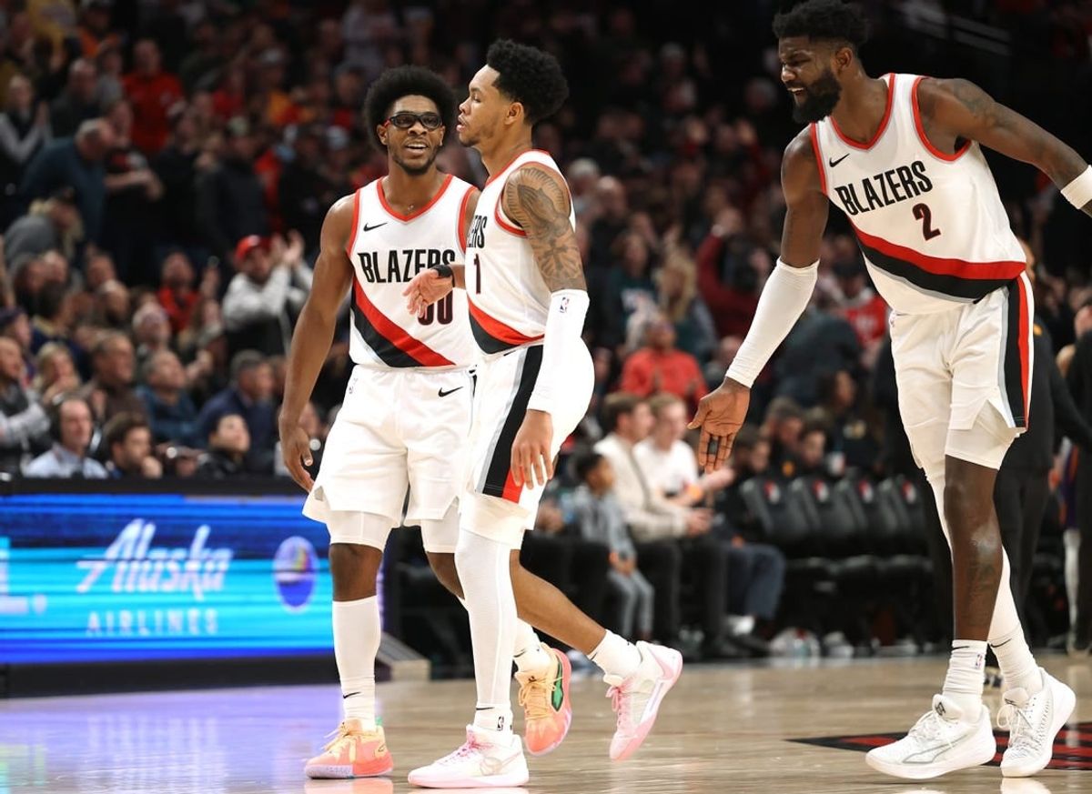 Dec 19, 2023; Portland, Oregon, USA;  Portland Trail Blazers guard Scoot Henderson (00), left, and center Deandre Ayton (2) celebrates with guard Anfernee Simons (1) after Simons scored a basket to seal the 109-104 win over Phoenix Suns at Moda Center.