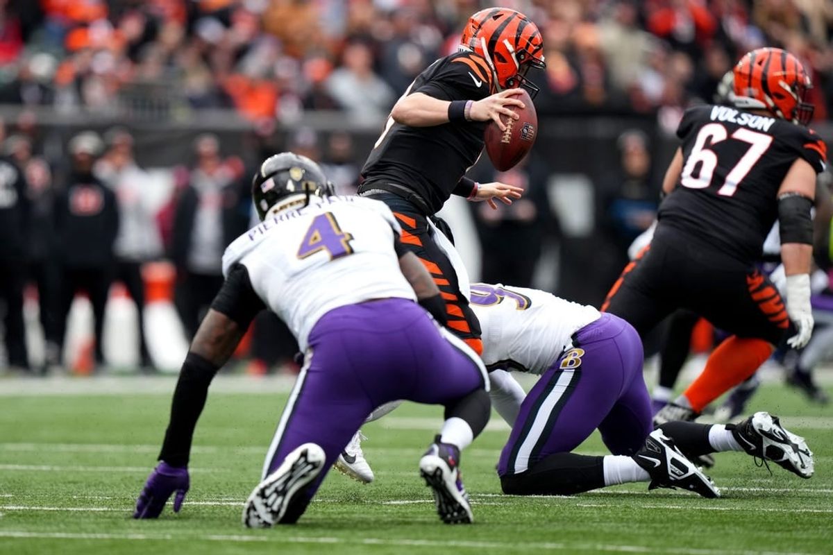 Jan 8, 2023; Cincinnati, Ohio, USA; Cincinnati Bengals quarterback Joe Burrow (9) avoids pressure by Baltimore Ravens linebacker Jason Pierre-Paul (4) in the first quarter at Paycor Stadium.