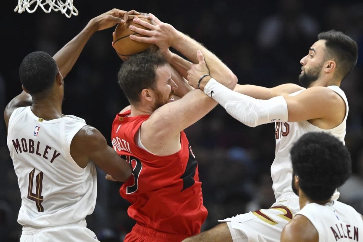 Nov 26, 2023; Cleveland, Ohio, USA; Cleveland Cavaliers forward Evan Mobley (4) and guard Max Strus (1) defend Toronto Raptors center Jakob Poeltl (19) in the second quarter at Rocket Mortgage FieldHouse.