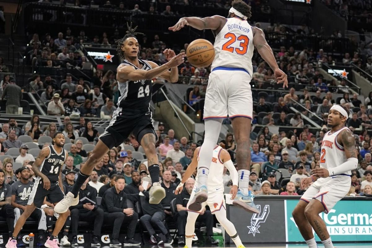 Mar 29, 2024; San Antonio, Texas, USA; San Antonio Spurs guard Devin Vassell (24) passed the ball against New York Knicks center Mitchell Robinson (23) during the first half at Frost Bank Center.