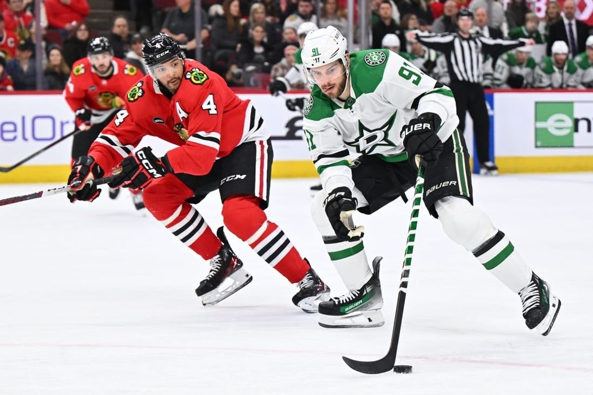 Jan 13, 2024; Chicago, Illinois, USA;  Dallas Stars forward Tyler Seguin (91) controls the puck while being defended by Chicago Blackhawks defenseman Seth Jones (4) in the second period at United Center.