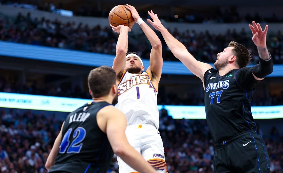 Feb 22, 2024; Dallas, Texas, USA; Phoenix Suns guard Devin Booker (1) shoots over Dallas Mavericks guard Luka Doncic (77) and Dallas Mavericks forward Maxi Kleber (42) during the second half at American Airlines Center.