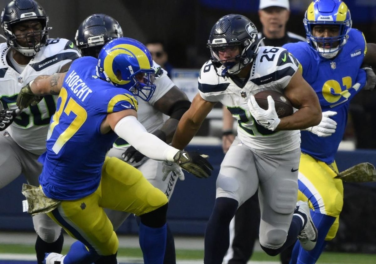 Nov 19, 2023; Inglewood, California, USA; Seattle Seahawks running back Zach Charbonnet (26) runs against Los Angeles Rams linebacker Michael Hoecht (97) in the first quarter at SoFi Stadium.