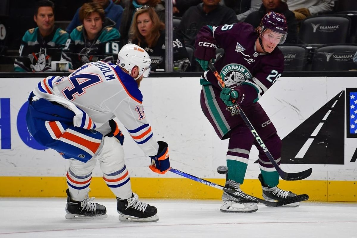 Dec 31, 2023; Anaheim, California, USA; Anaheim Ducks left wing Brock McGinn (26) passes the puck against Edmonton Oilers defenseman Mattias Ekholm (14) during the second period at Honda Center.