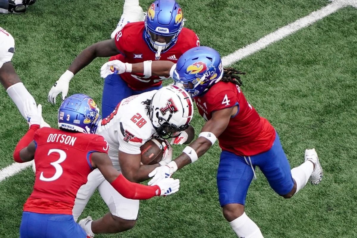 Nov 11, 2023; Lawrence, Kansas, USA; Kansas Jayhawks cornerback Mello Dotson (3) and safety Marvin Grant (4) tackle Texas Tech Red Raiders running back Tahj Brooks (28) during the first half at David Booth Kansas Memorial Stadium.