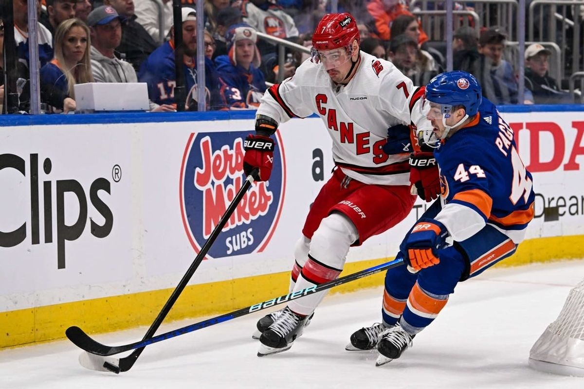 Apr 25, 2024; Elmont, New York, USA;  Carolina Hurricanes defenseman Dmitry Orlov (7) skates with the puck from behind the net defended by New York Islanders center Jean-Gabriel Pageau (44) during the second period in game three of the first round of the 2024 Stanley Cup Playoffs at UBS Arena.