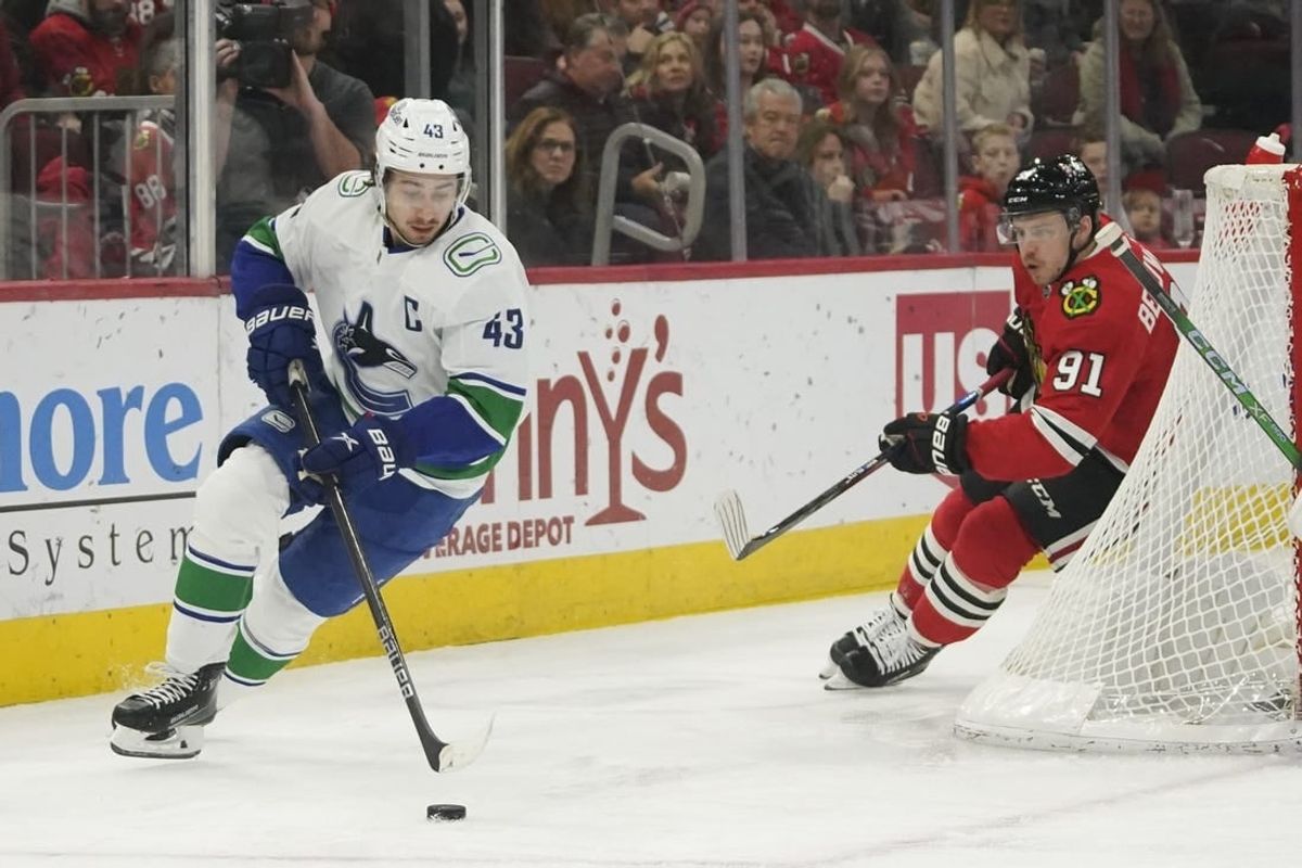 Dec 17, 2023; Chicago, Illinois, USA;   Vancouver Canucks defenseman Quinn Hughes (43) carries the puck chased by Chicago Blackhawks Anthony Beauvillier (91) during the first period at United Center.