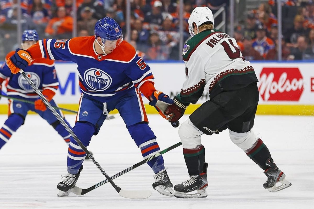 Apr 12, 2024; Edmonton, Alberta, CAN; Edmonton Oilers forward Dylan Holloway (55) and Arizona Coyotes defensemen Juuso Valimako (4) try to find a loose puck during the first period at Rogers Place.
