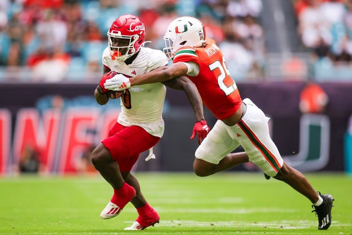 Nov 18, 2023; Miami Gardens, Florida, USA; Louisville Cardinals wide receiver Chris Bell (0) breaks a tackle attempt from Miami Hurricanes defensive back Jadais Richard (25) during the second quarter at Hard Rock Stadium.