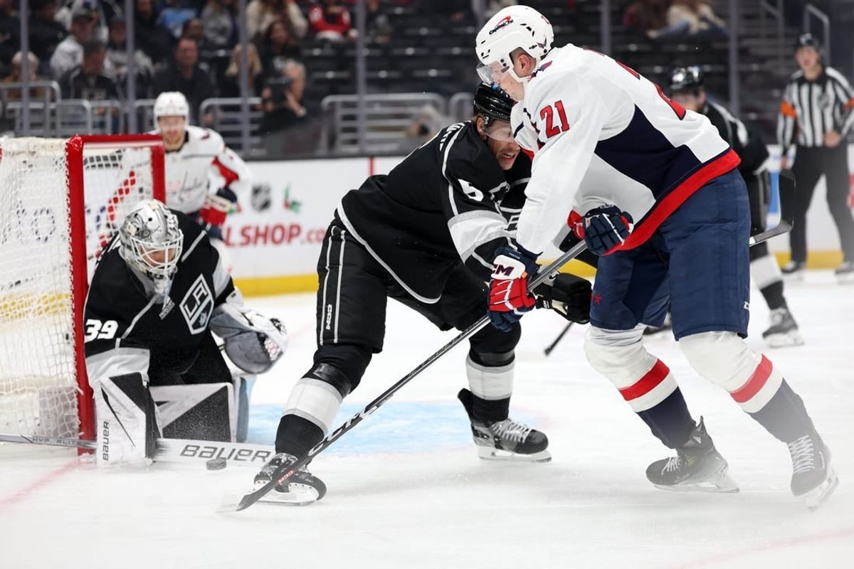 Nov 29, 2023; Los Angeles, California, USA; Washington Capitals center Aliaksei Protas (21) shoots the puck as Los Angeles Kings defenseman Andreas Englund (5) defends and goaltender Cam Talbot (39) protects the goal during the first period at Crypto.com Arena.