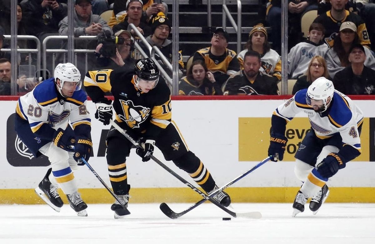 Dec 30, 2023; Pittsburgh, Pennsylvania, USA; Pittsburgh Penguins left wing Drew O'Connor (10) handles the puck against St. Louis Blues left wing Brandon Saad (20) and defenseman Nick Leddy (4) during the second period at PPG Paints Arena.