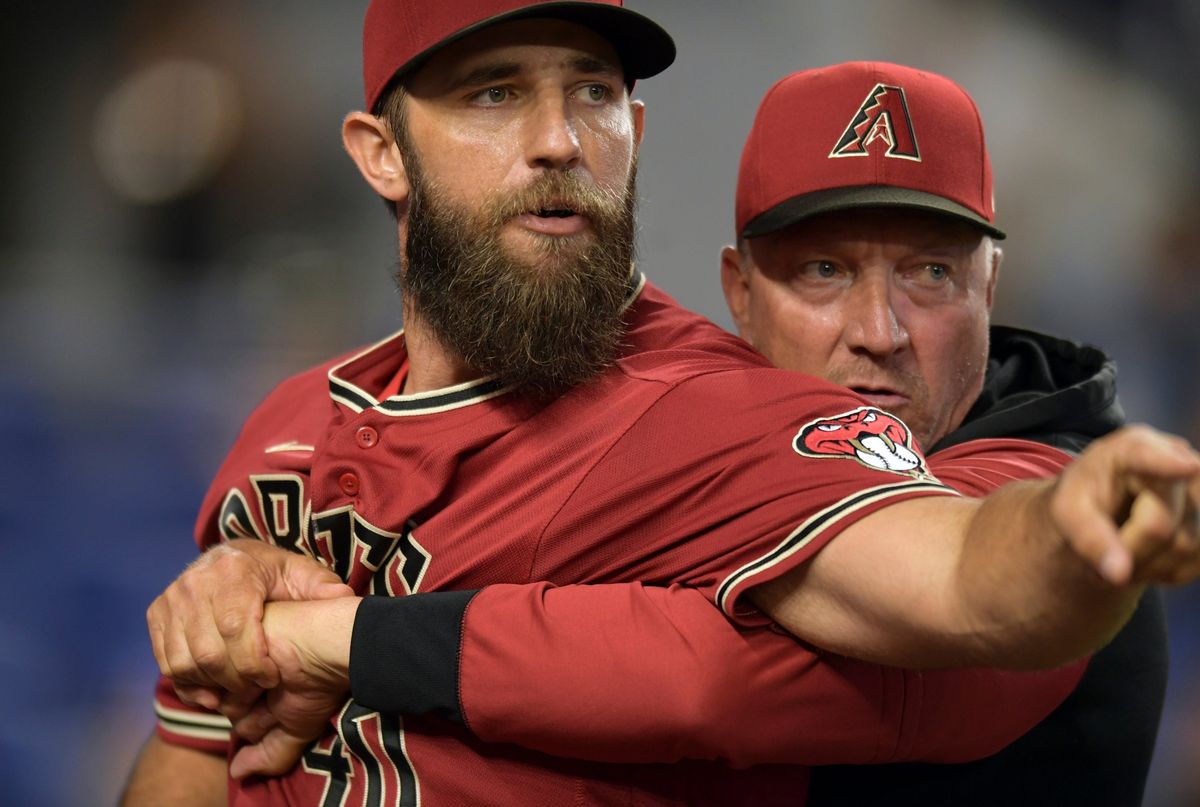 Madison Bumgarner is restrained by a coach.