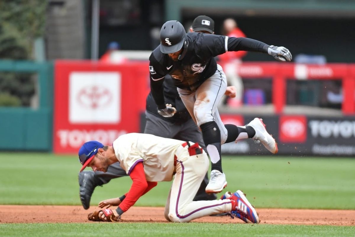 Apr 21, 2024; Philadelphia, Pennsylvania, USA; Chicago White Sox outfielder Kevin Pillar (12) leaps over Philadelphia Phillies shortstop Trea Turner (7) on his way to third base during the second inning at Citizens Bank Park.