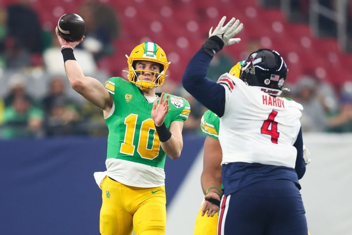 Jan 1, 2024; Glendale, AZ, USA; Oregon Ducks quarterback Bo Nix (10) throws the ball under pressure from Liberty Flames defensive tackle Jay Hardy (4) during the first quarter of the 2024 Fiesta Bowl at State Farm Stadium.