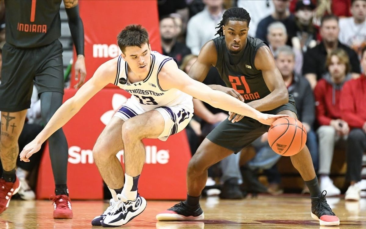 Feb 18, 2024; Bloomington, Indiana, USA;  Northwestern Wildcats guard Brooks Barnhizer (13) reaches for the ball in front of Indiana Hoosiers forward Mackenzie Mgbako (21) during the first half at Simon Skjodt Assembly Hall.