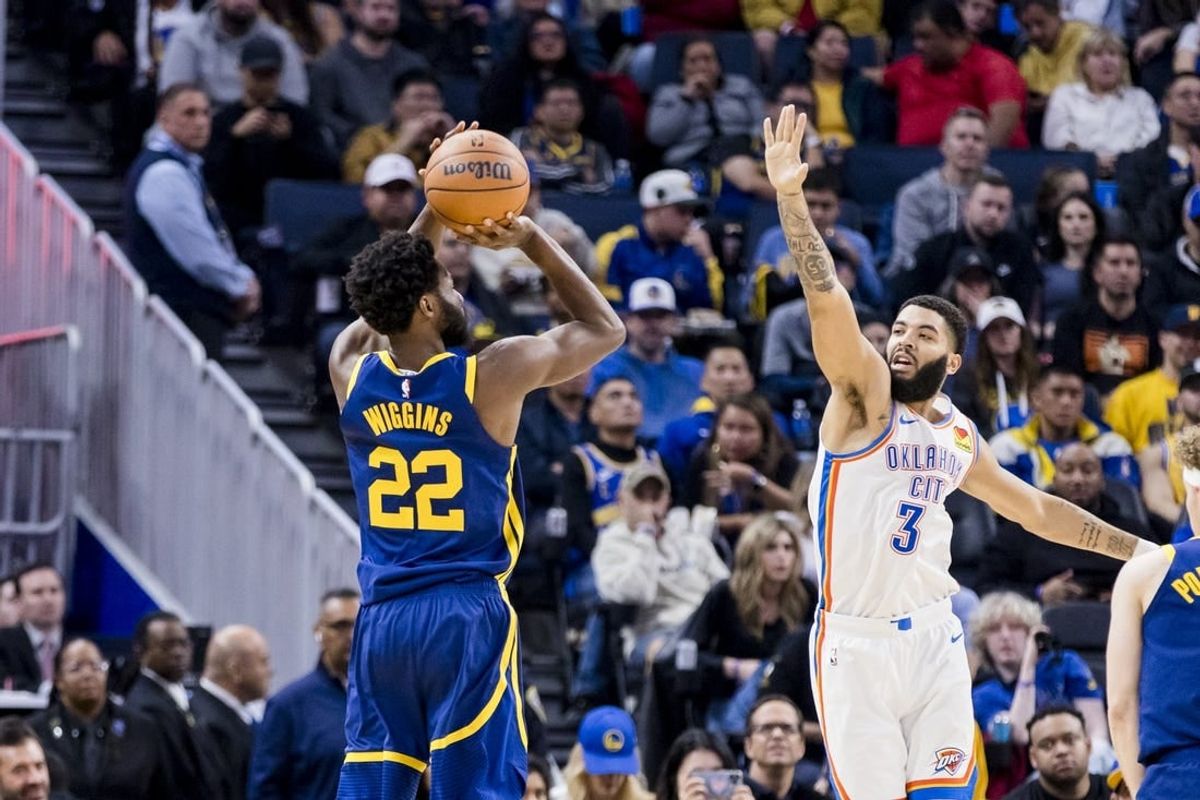 Nov 18, 2023; San Francisco, California, USA; Golden State Warriors forward Andrew Wiggins (22) takes a three-point shot as Oklahoma City Thunder guard Josh Giddey (3) defends during the first half at Chase Center.