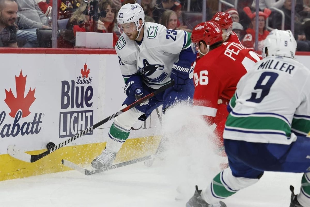 Feb 10, 2024; Detroit, Michigan, USA;  Vancouver Canucks center Elias Lindholm (23) skates with the puck defended by Detroit Red Wings defenseman Jeff Petry (46) in the third period at Little Caesars Arena.