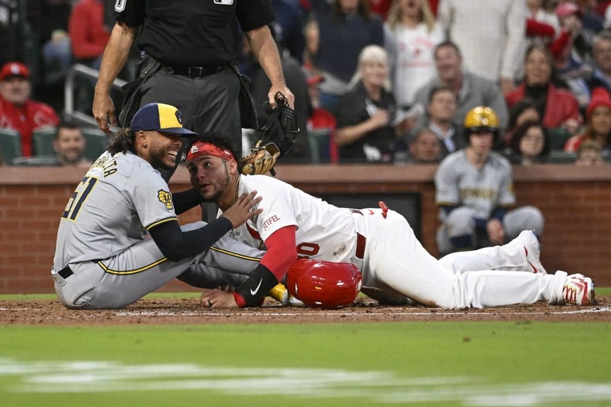 Apr 19, 2024; St. Louis, Missouri, USA; Milwaukee Brewers pitcher Freddy Peralta (51) laughs with St. Louis Cardinals catcher Willson Contreras (40) after tagging Contreras out at home plate in the second inning at Busch Stadium.