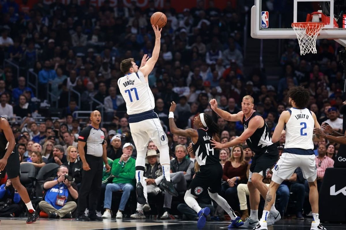 Apr 23, 2024; Los Angeles, California, USA; Dallas Mavericks guard Luka Doncic (77) shoots the ball over Los Angeles Clippers guard Terance Mann (14) during the first quarter of game two of the first round for the 2024 NBA playoffs at Crypto.com Arena.